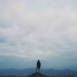 Rear view of silhouette man standing on mountain against sky