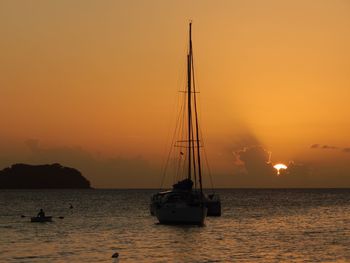 Sailboat sailing on sea against orange sky