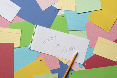 High angle view of colorful papers with text and pencil on table