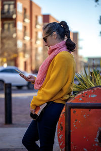 Side view of woman using mobile phone on footpath