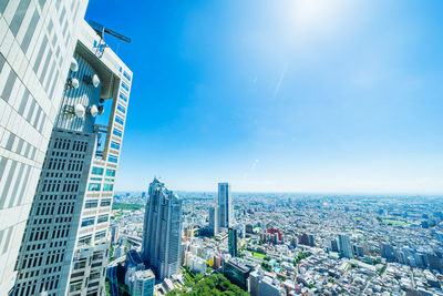 Aerial view of buildings in city against blue sky