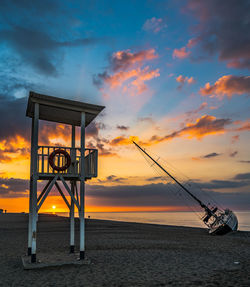 Lifeguard hut on beach against sky during sunset