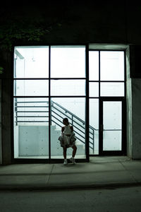 Full length of woman standing on sidewalk by building at night