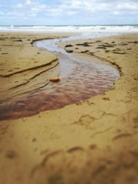 Close-up of sand at beach against sky