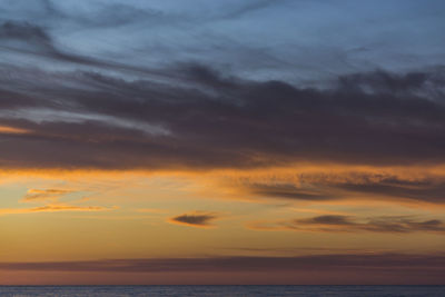 Scenic view of sea against dramatic sky during sunset