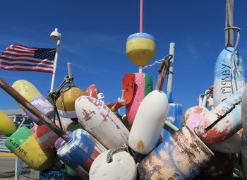 Low angle view of colorful buoys against blue sky during sunny day