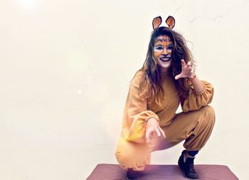 Full length portrait of happy woman wearing costume on seat against white background