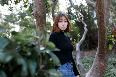 Portrait of woman standing by tree