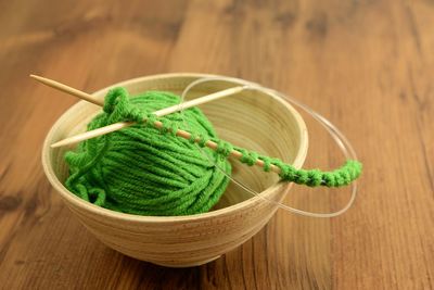 Close-up of knitting needle and wool in bowl on table