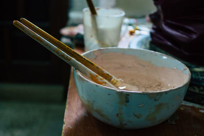 Close-up of hand holding bowl on table