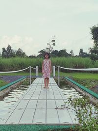 Rear view of woman standing by trees against sky