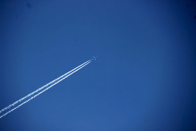 Low angle view of airplane flying against clear blue sky