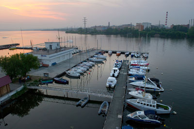 Boats moored at harbor during sunset