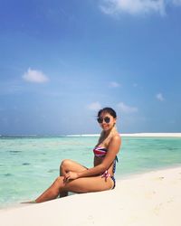 Portrait of woman at beach against sky