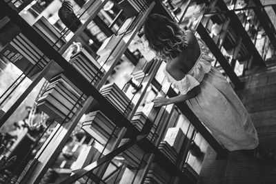 High angle view of woman standing at bookshelf in library