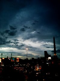 Illuminated cityscape against cloudy sky