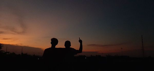 Rear view of silhouette people standing against sky during sunset