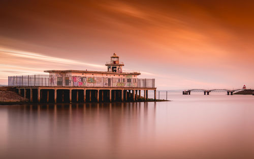 Pier over sea against sky during sunset