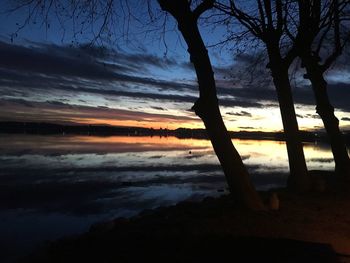Silhouette trees by lake against sky during sunset
