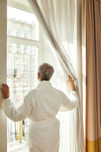 Rear view of man looking through window