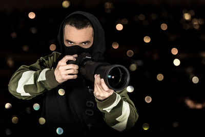 Portrait of man holding camera at night