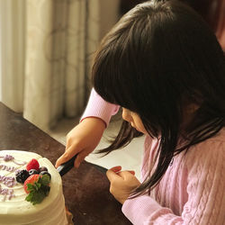 Side view of girl cutting cake