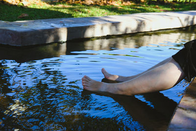 Low section of woman sitting at pond