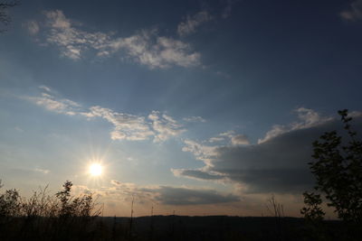 Low angle view of sunlight streaming through clouds