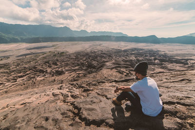 Rear view of man sitting on landscape