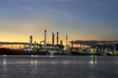 Illuminated factory against sky during sunset