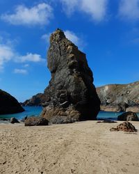 Rock formations on beach against sky