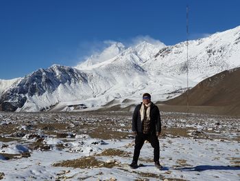 Full length of woman standing on land by snowcapped mountain against sky
