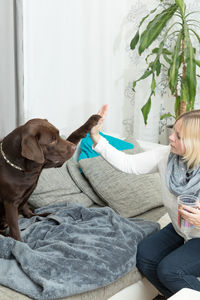 Woman and dog giving high-five at home