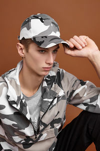 Portrait of young man wearing hat against gray background