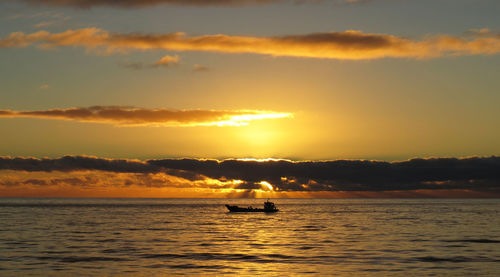 Sailboat sailing on sea against sky during sunset