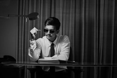 Young man sitting at table with business costume wearing tie and shirt