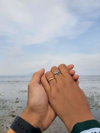 Midsection of couple kissing on beach against sky