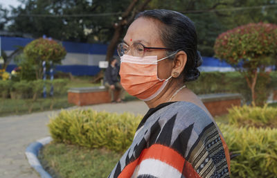 Portrait of an aged bengali woman wearing face mask during her visit at rabindra sarobar flower show