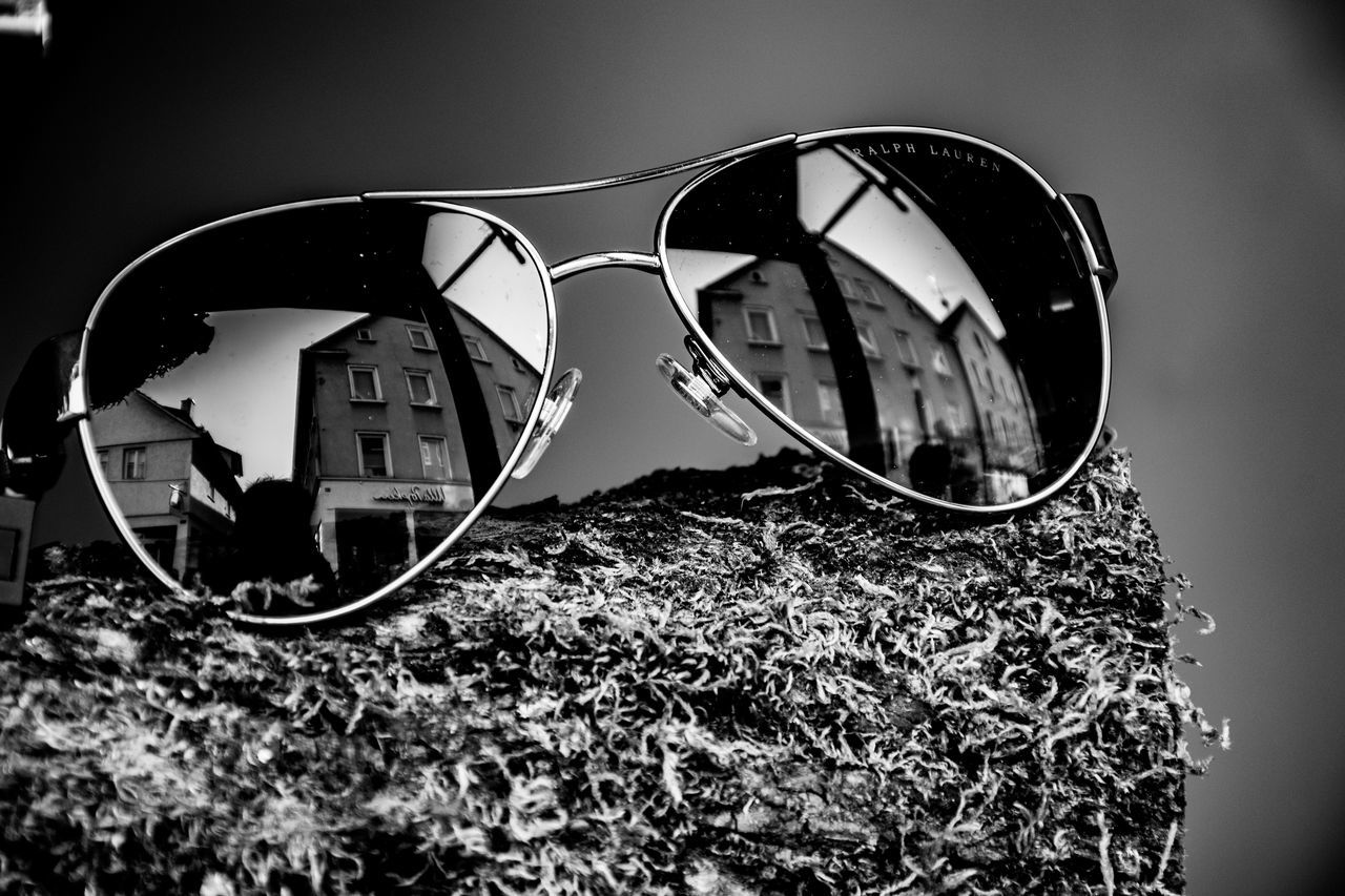 CLOSE-UP OF SUNGLASSES WITH REFLECTION ON GLASS