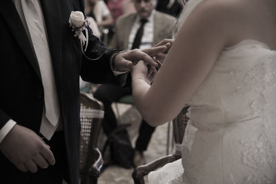 Midsection of bride inserting wedding ring in bridegroom finger