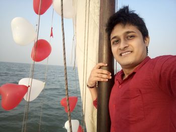 Portrait of smiling man sailing in decorated boat on sea against sky