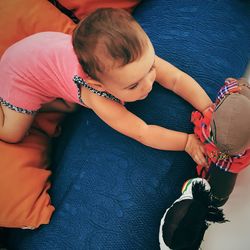 High angle view of baby girl playing with toys on bed