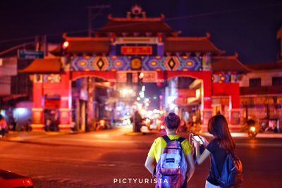 Rear view of people on illuminated street at night