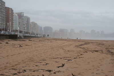 Panoramic view of beach and buildings against sky in mist 