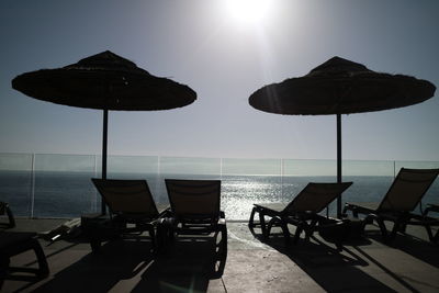 Empty chairs and table on beach against clear sky