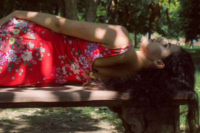Midsection of woman with red hair against trees