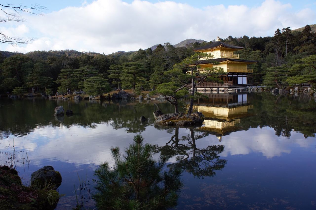 tree, building exterior, sky, water, architecture, built structure, reflection, cloud - sky, lake, tranquil scene, mountain, tranquility, house, cloud, nature, scenics, beauty in nature, waterfront, standing water, day