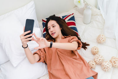 Young woman using mobile phone on bed at home