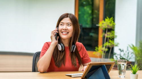 Young woman using phone while sitting on table