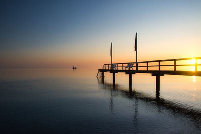 Pier on sea against sky during sunset